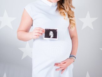 pregnant woman holding ultrasound photo of unborn child