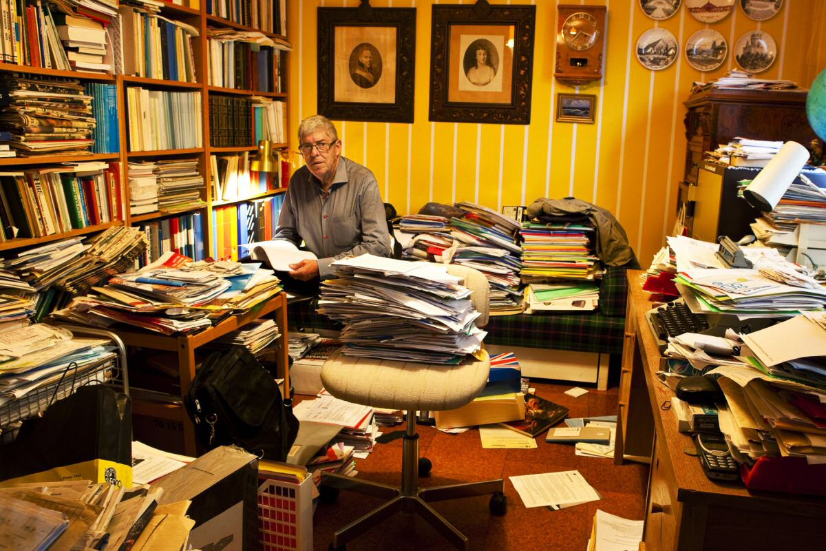 cluttered room with man reading